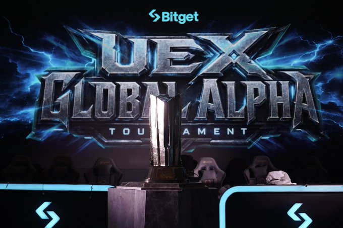 A gleaming trophy sits center stage beneath an electrifying "Bitget UEX Global Alpha Tournament" backdrop with glowing blue lightning effects, with gaming chairs and merchandise visible around it—capturing the event's "Ready Player One" theme and competitive atmosphere shared in the post.