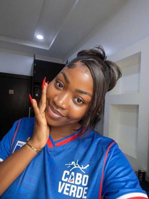 A woman wearing a blue "CABO VERDE" soccer jersey poses with her hand on her cheek, flashing a bright smile and red manicure in what appears to be a hotel or apartment room.

The image pairs with the "GM CT happy Friday" caption by showcasing her cheerful, relaxed vibe for a Friday greeting, with the Cabo Verde jersey possibly hinting at a connection to Cape Verde or her support for the national team.