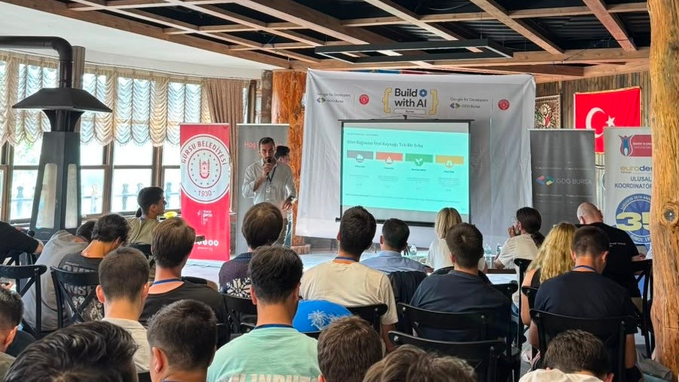 A photograph of a presentation at a 'Build with AI' event, showing an audience watching a speaker presenting about 'Crew Engineer Methodology: True SSO Test Bed' with Turkish university banners visible.