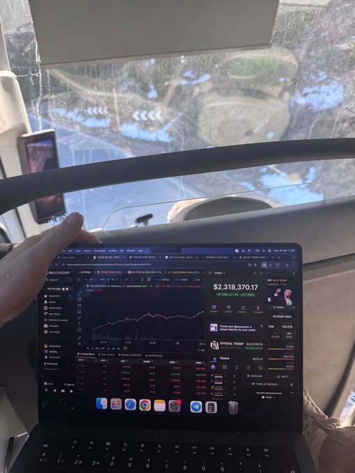 A person using a MacBook displaying a TradingView chart showing a portfolio value of $2,318,370.17 with a green daily gain of +$194,227.90 (+9.11%), seated on a bus with a rainy window view.