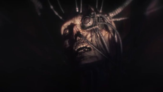 The image shows a close-up view of a skull with its mouth open, revealing teeth that appear to be grinding against each other. The skull's face is illuminated by a beam of light, creating an eerie glow around it. The background is dark and out of focus, drawing attention to the skull in the foreground. The caption above the image reads "The World Computer writhes invisibly with power from an Enlightened Age of Belief." This suggests that the skull might be associated with a powerful or mysterious figure from history who was shrouded in darkness but held up by the light of knowledge and wisdom.