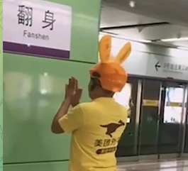 A person in a yellow T-shirt and an orange animal-eared hat takes a photo in front of a subway station sign that reads "翻身" (Fanshen, meaning "turn over" or "transform one's fate"), which serves as a fitting visual metaphor for the post's theme of transforming a small $3,000 trading account into $100,000.