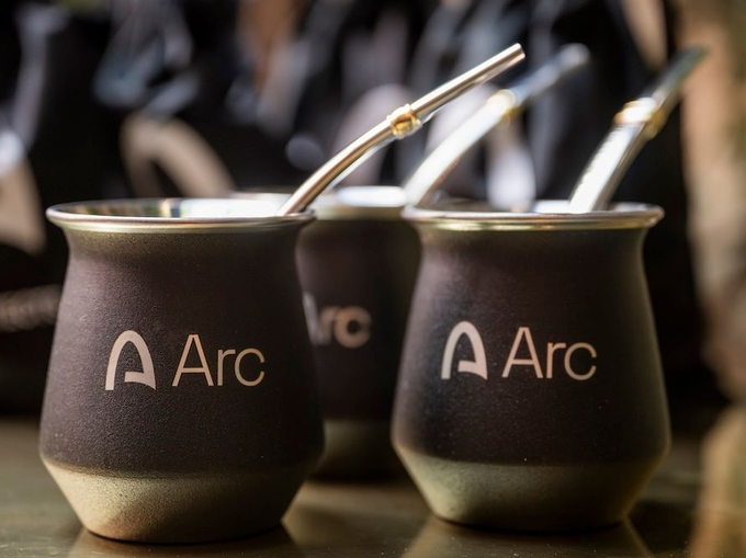 Three black matte mate gourds branded with 'A Arc' logo, each with a metal bombilla straw, sitting on a wooden surface.