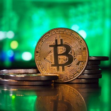 A physical Bitcoin token stands prominently against a green digital backdrop, symbolizing the cryptocurrency's market movements. The image pairs with Glassnode's analysis highlighting Bitcoin's critical supply wall between $81K-$86K, where long-term holder breakeven levels and sell orders could challenge the rally.