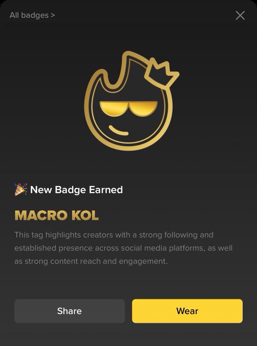 A notification from Binance Square celebrating the "Macro KOL" badge, featuring a gold flame emoji character wearing a crown, with options to "Share" or "Wear" the badge — corresponding to the post announcing the achievement and encouraging others to follow and start creating on the platform.