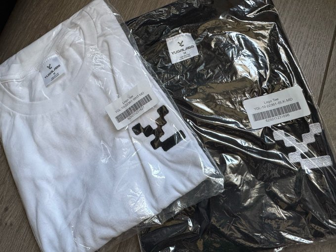 Two folded t-shirts in plastic packaging, one white and one black, both with "YUSHUANG" branding and logo tags.