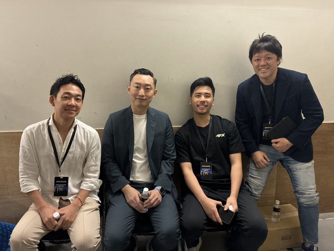 Four men smiling and posing for a photo at what appears to be a conference, wearing lanyards with 'SPEAKER' badges.
