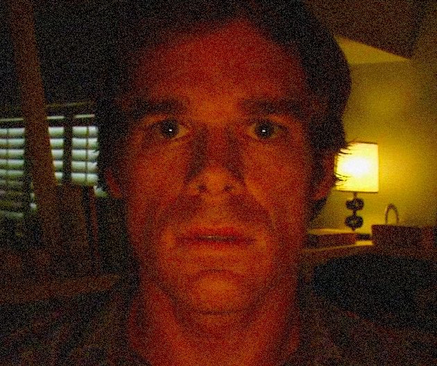 The image shows a close-up of a man's face, capturing his red skin tone with a reddish hue that appears slightly yellowed as if taken at sunset or near a lamp. The image also contains an overlay of text related to a post about vulnerabilities and a quote from Mythos. A person's head is visible in the foreground, while the background features a wall and another individual who seems to be looking away from the camera.