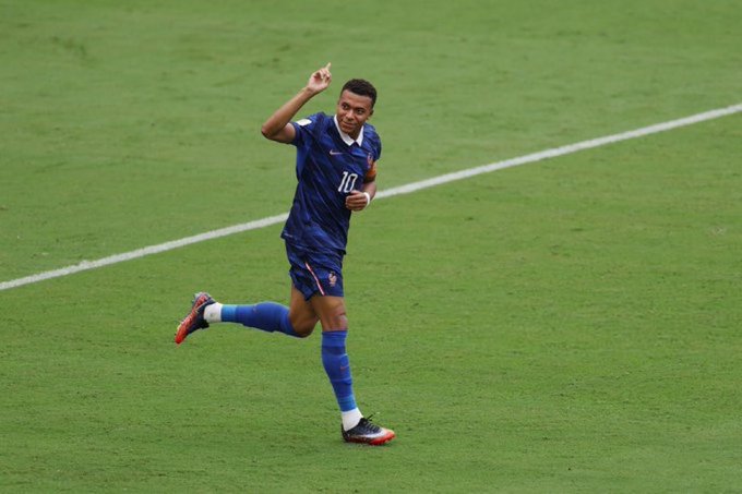 A soccer player in a dark blue Netherlands kit with the number 10 celebrating on a green field.