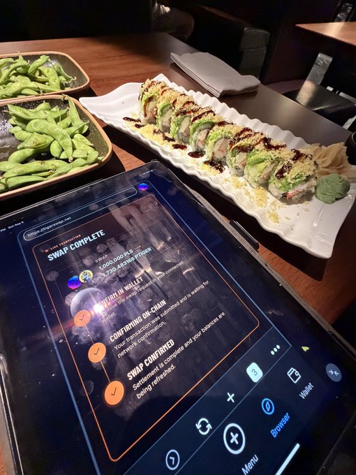 A sushi roll platter sits on a table next to edamame and an iPad displaying a cryptocurrency swap interface completing a transaction between currencies, with visible text including 'SWAP COMPLETE' and 'CONFIRMING ON-CHAIN'.