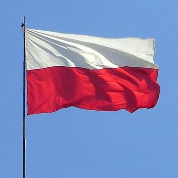 The image shows the Polish flag—white on top and red on bottom—waving against a clear blue sky, symbolizing Poland in the context of its parliament's failure to override the president's veto of a cryptocurrency bill, leaving the nation's crypto industry in regulatory limbo.