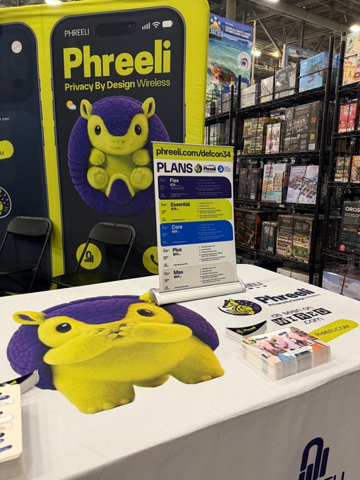 A trade show booth for 'Phreeli - Privacy By Design Wireless' features a yellow and purple color scheme with a mascot character and displays pricing plans ranging from 'Flex' to 'Max' with promotions referencing 'phreeli.com/defcon34'.