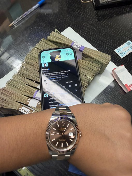 The image shows a person's wrist wearing a Rolex Oyster Perpetual Datejust watch in front of a smartphone displaying a Twitter feed (featuring @vcabor), all resting on stacks of banded cash including $500 bills. The post's "Uptember" caption aligns with the image's display of wealth and crypto/finance Twitter content, suggesting bullish market sentiment and financial success.