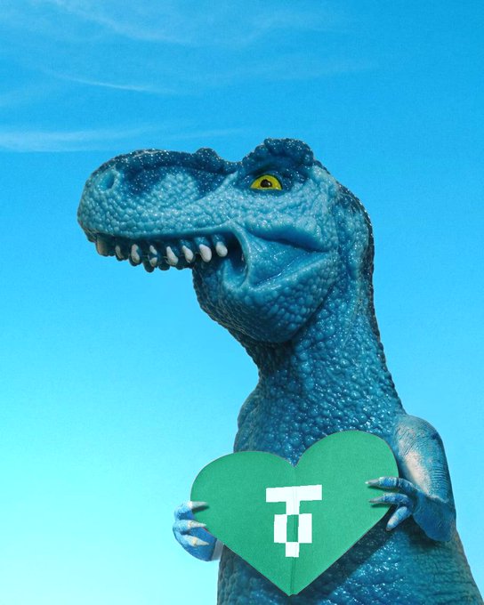 A blue toy dinosaur holds a green heart-shaped sign featuring the Tether (USDT) "₮" logo, symbolizing the ongoing support from the @Stable and @tether teams highlighted in the $FEFER project update.