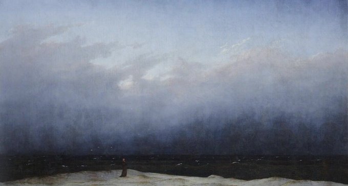 A lone figure stands on a snowy shore beneath a vast, moody sky where soft light breaks through the clouds, reflecting the contemplative awe of "Heaven smiles above me."
