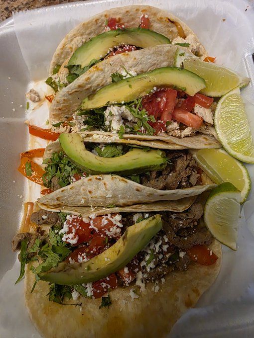 Three soft tacos filled with shredded meat, avocado slices, diced tomatoes, cilantro, and crumbled cheese, served alongside lime wedges in a styrofoam takeout container. The image shows the meal the poster is providing in exchange for SOL crypto wallet donations.