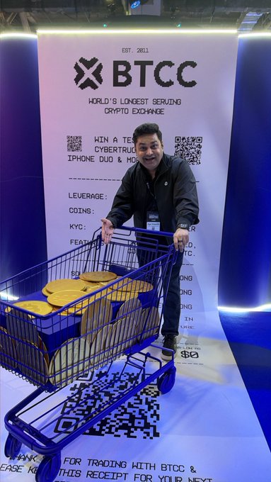 A man pushing a shopping cart filled with large gold Pi cryptocurrency coins in front of a backdrop for BTCC, described as the 'World's Longest Serving Crypto Exchange', established in 2011.