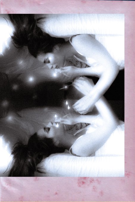The image features a woman with long brown hair lying down, holding her hand up to her face as if she's looking at herself in the mirror. The photo has been edited or photoshopped into two separate images, creating an interesting visual effect that makes the viewer question whether it is one person or two individuals sharing the same space.

The post includes a caption that reads "gm forever the lightkeeper 10 tezos". This phrase might be a reference to the artist's name or could be related to the image in some way. The image has been edited, and the woman appears to be looking at herself in the mirror, which adds an element of intrigue to the overall composition.

The photo is described as being "very blurry", which may contribute to its artistic appeal and make it more visually interesting.