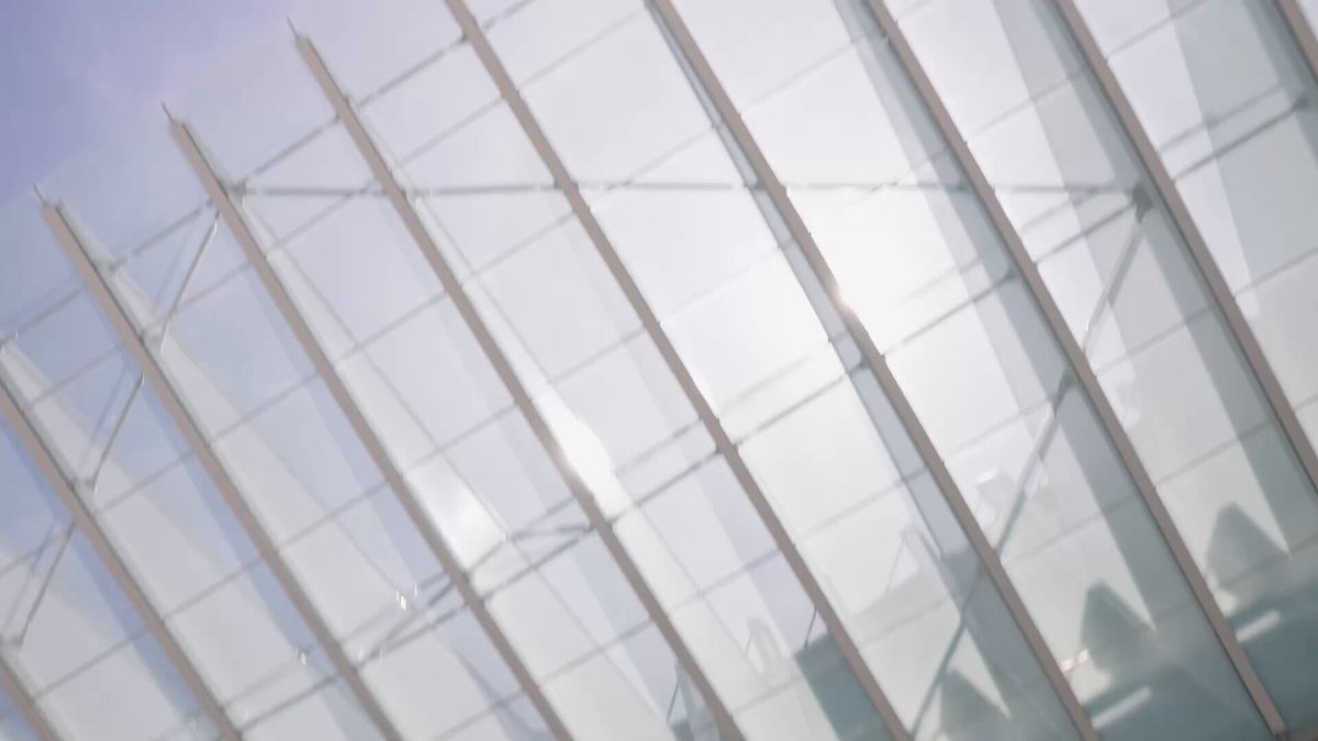 The image shows a modern, abstract glass building that has an interesting design with numerous lines across its surface. The perspective of the photo appears flat as if seen from ground level, with no discernible actions or characters taking place. The main focus is on the architectural features and the text in the post above the scene providing information about open infrastructure and security measures to protect it.
