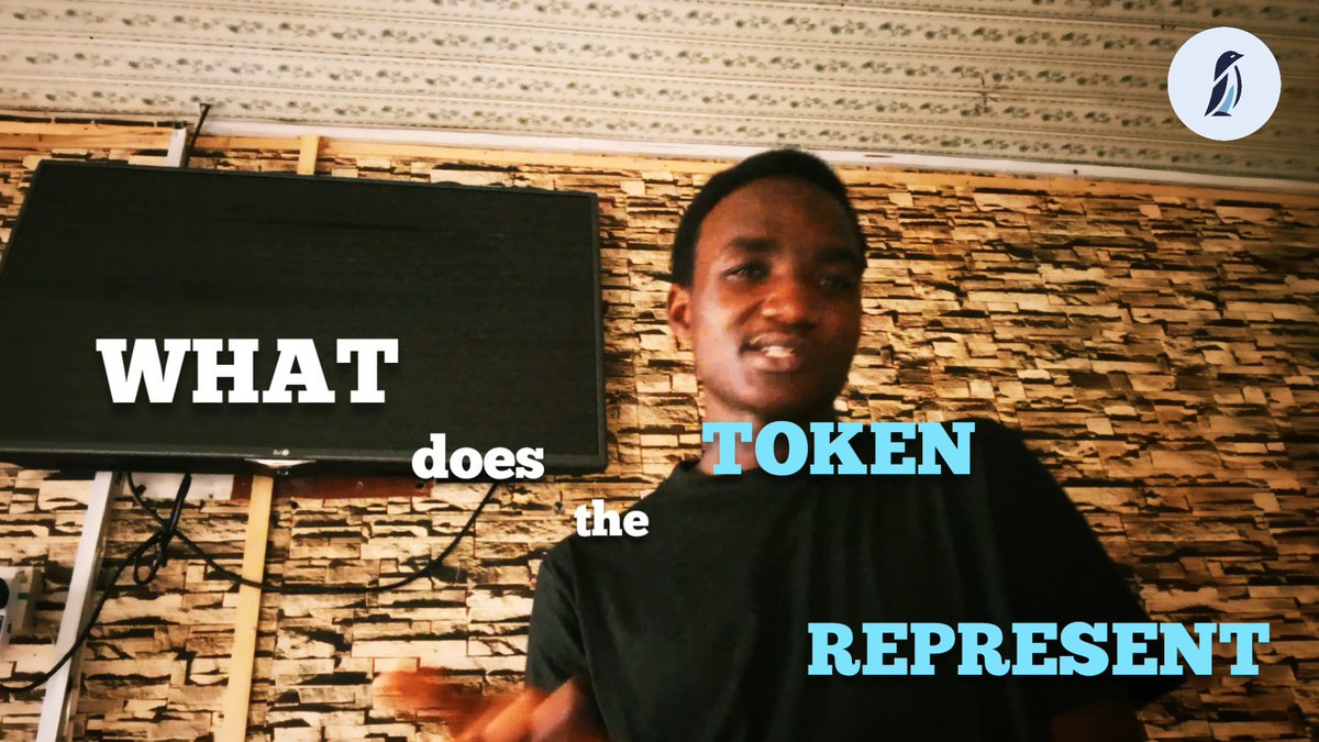 A young man in a black shirt stands in front of a textured stone wall with a TV, with text overlay reading 'WHAT does the TOKEN REPRESENT' in white and blue, and a penguin logo in the corner.