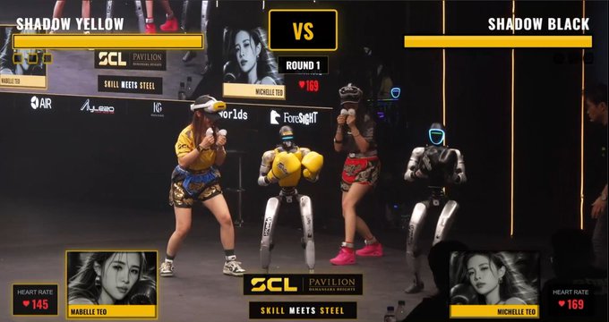 An SCL Pavilion boxing match screen showing 'SHADOW YELLOW vs SHADOW BLACK' with fighters and robots in a ring, featuring heart rates of 145 and 169 for Mabelle Ted and Michelle Ted respectively.