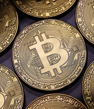 A close-up image of multiple gold-colored Bitcoin coins, with the central coin prominently displaying the iconic "B" symbol and circuit-like design, visually representing the concept of a solo Bitcoin miner successfully mining a block. The image complements the news of the rare solo mining achievement by symbolizing the digital currency reward earned through independent block validation.