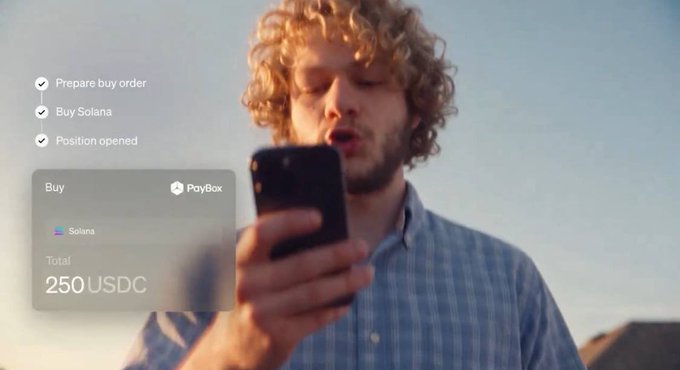 A young man with curly blond hair gazes at his phone, with an overlaid interface showing a completed transaction checklist (Prepare buy order, Buy Solana, Position opened) and a PayBox purchase screen confirming a Buy of Solana totaling 250 USDC. The image visually reinforces the headline by depicting a user easily engaging in Solana-based trading through MoonPay's PayBox integration on Grok.