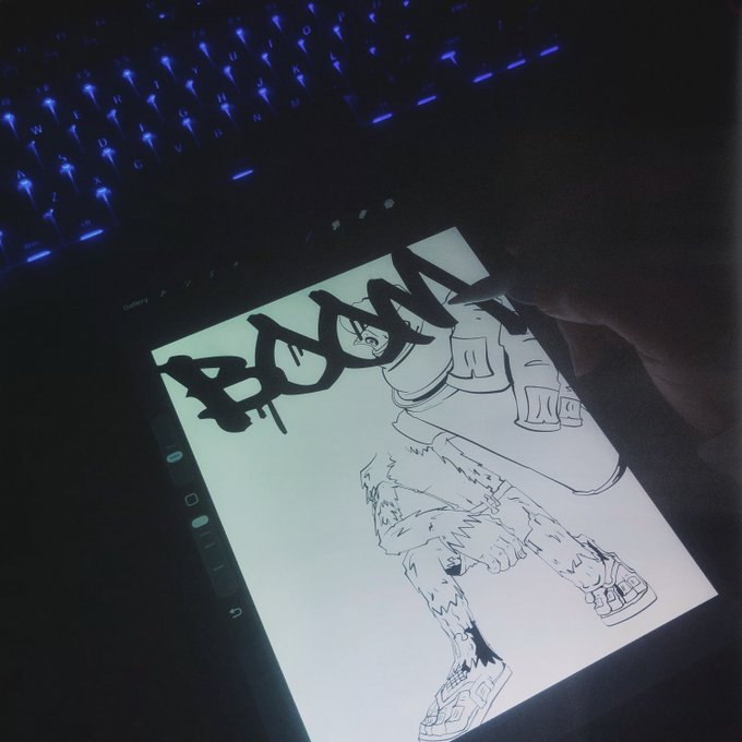 A hand drawing graffiti-style black lettering on a digital tablet screen displaying a sketch of sneakers, with a blue-backlit keyboard visible in the background.