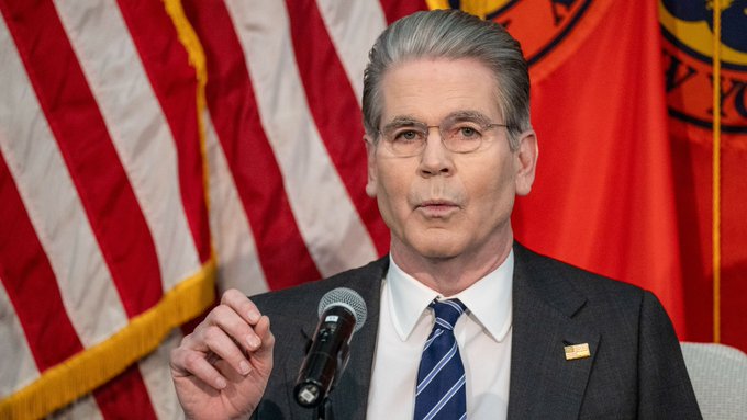Treasury Secretary Scott Bessent speaks at a podium, with American flags and an official Treasury seal visible behind him, as the accompanying post highlights his remarks on the CLARITY Act progressing toward a Senate vote—a development being celebrated by XRP holders.