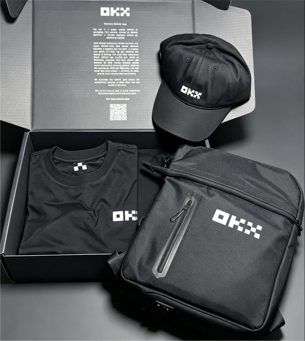 Black OKX merchandise unboxing featuring a branded baseball cap, folded t-shirt, and backpack inside an OKX gift box.
