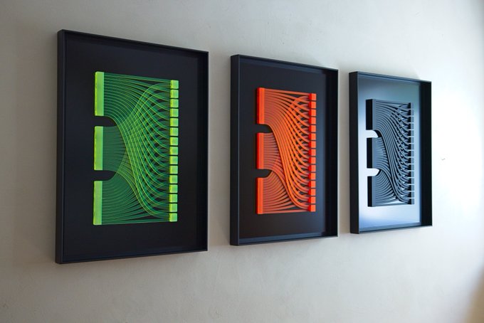 Three framed string-art pieces mounted on a white wall, each depicting the letter 'E' in green, orange, and black/white color schemes.