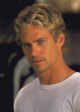 A blond man wearing a white t-shirt gazes directly at the camera with an intense expression. The image appears to depict Paul Walker, the late actor from the Fast & Furious franchise, as referenced in the accompanying post about potentially using AI to recreate him for future films.