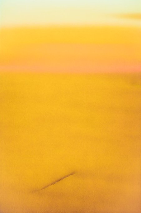 An abstract artwork featuring a warm, blurred gradient of yellow and peach tones with subtle horizontal bands of color.