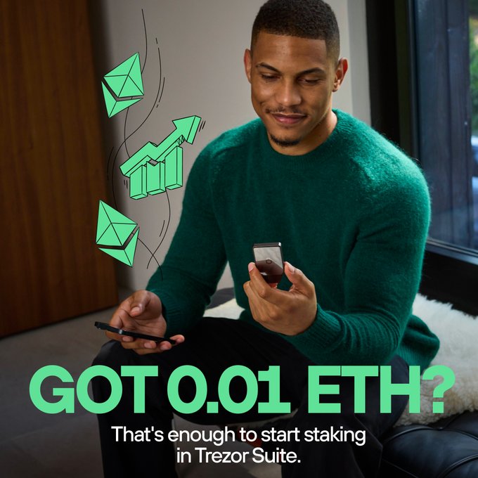 A man in a green sweater smiles while holding a smartphone and a Trezor hardware wallet, with the text "GOT 0.01 ETH? That's enough to start staking in Trezor Suite" overlaid alongside illustrations of Ethereum logos and a rising growth chart. The image promotes Trezor's staking feature, complementing the post's tip on securing Trezor devices with COLDCARD child seeds to protect crypto holdings like ETH.