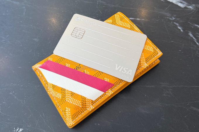 A silver Plasma Visa card rests on top of a yellow snakeskin-patterned cardholder, displayed to advertise that the physical Plasma card is now available for application. This visual pairs with promotional text highlighting its compatibility with major platforms like WeChat and Alipay.