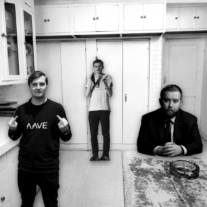 A black and white photograph of three men in a kitchen setting; the man on the left wears a sweater reading 'AAVE', while another man's head appears overlaid on the right side of the image.