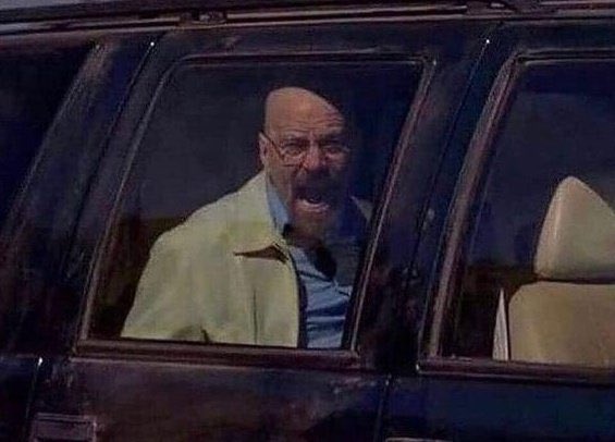 An older man with glasses, looking distressed or shouting, sits in the driver's seat of a dark vehicle.