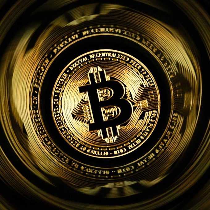 A close-up, dramatic shot of a golden Bitcoin coin featuring the iconic "B" symbol and inscriptions like "BITCOIN DIGITAL DECENTRALIZED PEER TO PEER," visually representing the cryptocurrency strategy that helped the 92-year-old burger chain achieve a 13.8% sales jump.