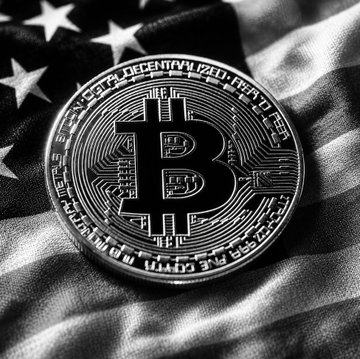 A physical Bitcoin token rests atop an American flag, symbolizing Bitcoin's growing prominence in the U.S. financial landscape—visually reinforcing Anthony Scaramucci's prediction of a Bitcoin rally in late 2026 into early 2027, with the coin's inscriptions reading "Bitcoin," "Fine Copper," and "Vires in Numeris."