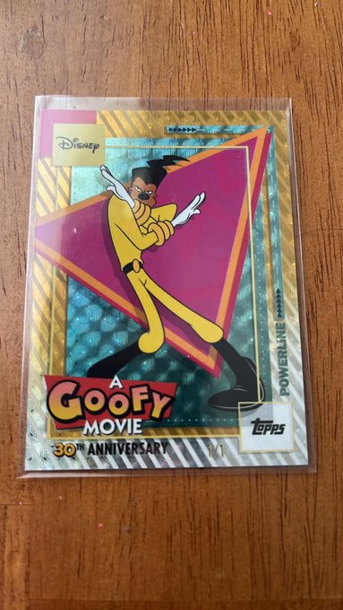 The image features a small, clear plastic card with a cartoon character from "Goofy Movie" on it. The card has a pink background and yellow accents, giving it a playful and nostalgic appearance. The text on the card reads "A Goofy Movie", which is likely related to the movie "Powerline". The image also includes a small amount of text that says "30th Anniversary", suggesting that this card might be from an anniversary celebration or a special edition release.