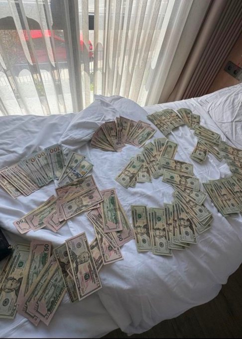 The image shows a large amount of money, specifically US dollar bills, spread out across a white bedspread or comforter. The text in the image reads "Guess how much this is and get 1 $SOL Only if you're right". This suggests that there might be an element of mystery or challenge involved with the money, possibly involving a game or contest where participants need to guess the correct amount within a specific time frame.

The bedspread appears to be white, which contrasts nicely with the colorful bills and makes them stand out. The image also includes a car visible in the background, adding an interesting detail to the scene.