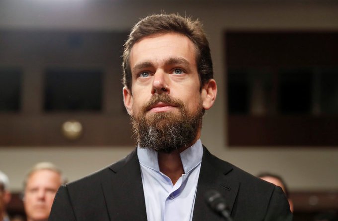 A bearded man in a dark suit and light blue shirt stands at a microphone with a serious expression, appearing to address an audience. The image accompanies a post attributed to Jack Dorsey predicting Bitcoin will surpass $1,000,000 by 2030.