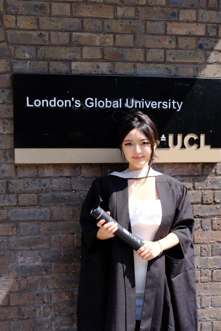 A young woman in graduation robes poses in front of the UCL (London's Global University) sign, holding her diploma in front of a brick wall. The image corresponds to the caption about graduating from UCL in December 2025, marking a milestone in her diverse career path spanning Deloitte, Tencent, and various Web3 and fintech companies.