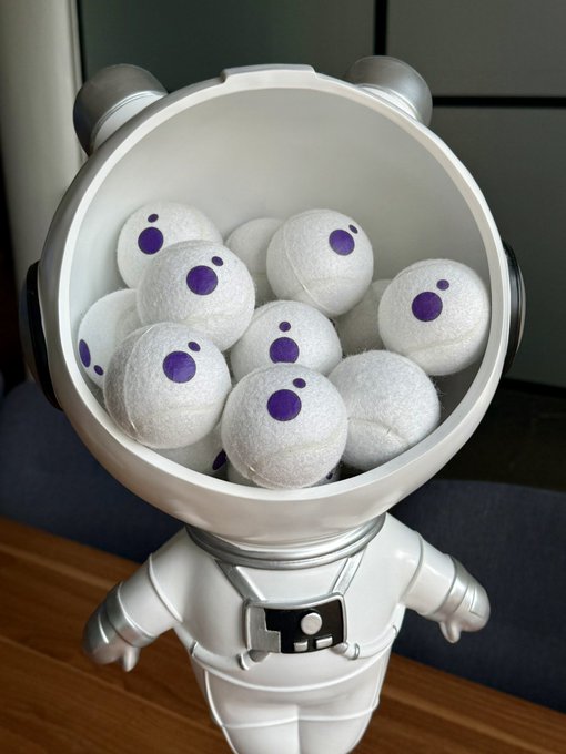 A luxury astronaut figurine holds a jar filled with white golf balls marked with purple dots resembling logos, whimsically tying the MoonPay brand to the playful "to the moon" space and golf imagery.