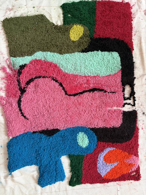 A colorful, textured artwork resembling a rug or painting features abstract, biomorphic shapes in shades of pink, blue, green, and black.