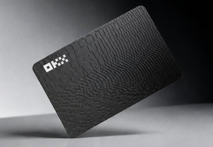 A sleek black OKX card with an embossed fingerprint-like pattern is displayed against a dark background, featuring the white "OKX" logo in the upper left corner. The image relates to the post promoting the OKX Card Visa as a stylish payment method for dining out, even on a first date.