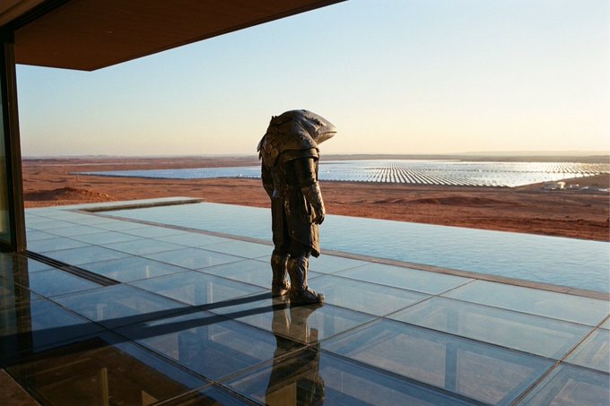 The image shows a man standing on a glass patio or deck, overlooking a body of water with the Solana cryptocurrency displayed prominently in the background. The man appears to be wearing scuba gear, which might suggest that he is an underwater explorer or scientist. The photo has been captioned by someone who loves Bitcoin and blockchain technology, expressing their interest in it and possibly providing insights into its potential applications or future developments within the crypto space.