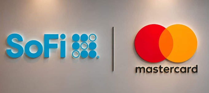 The SoFi and Mastercard logos are displayed side-by-side on a wall, representing their new partnership to bring stablecoin settlement into live operation—a move that bridges traditional finance with blockchain-based payments. The image visually reinforces the post's message about these two financial giants integrating onchain settlement into mainstream payment infrastructure.