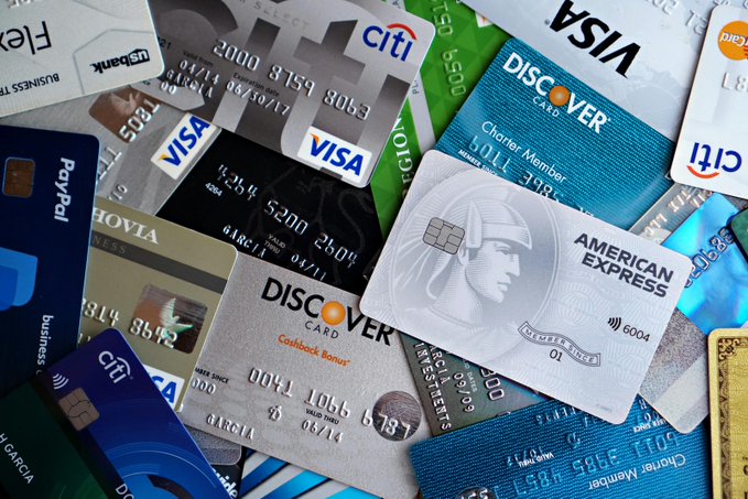 A scattered pile of various credit and debit cards from issuers including Visa, Citi, Discover, American Express, and PayPal, alongside stablecoin-linked payment cards, illustrates the growing convergence of traditional banking and digital currency payments that drove the $759M in crypto card transactions reported for July.