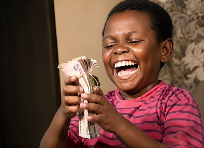 A photograph of a young boy in a pink striped shirt joyfully laughing with eyes closed while holding a thick stack of cash.
